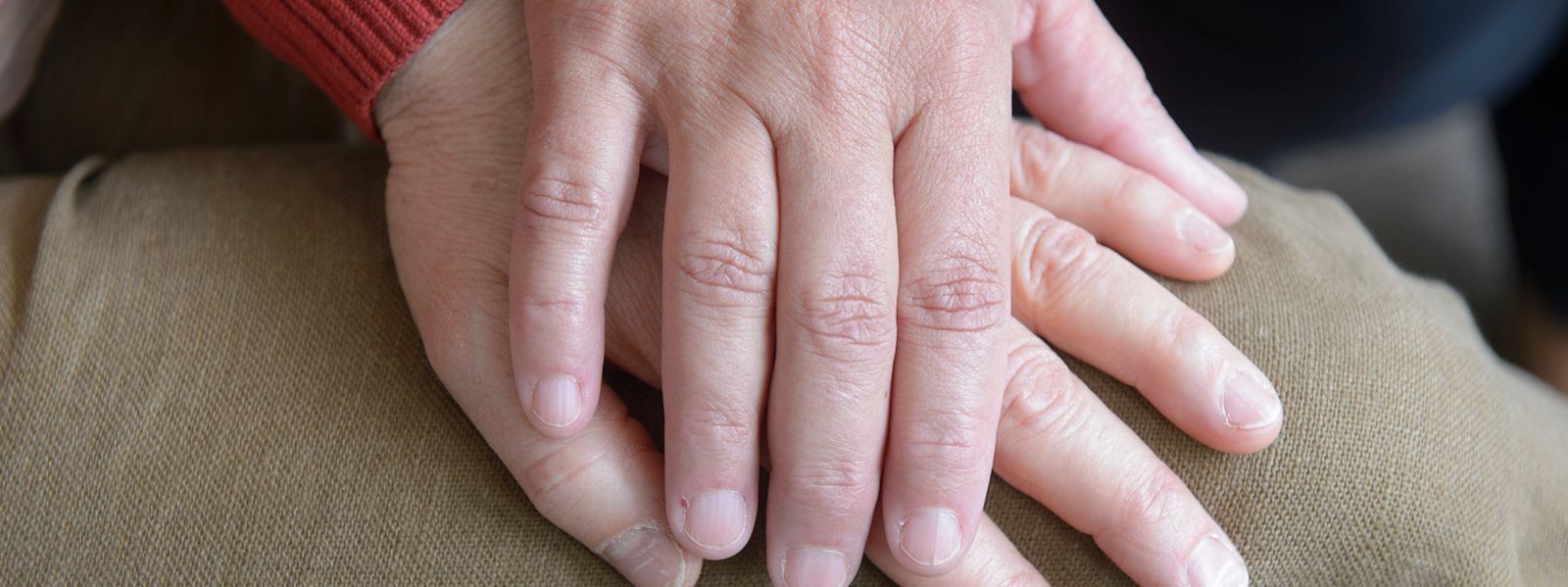 Hand die auf einem Bein abgelegt ist, wird von einer anderen Hand ergriffen Slider-Palliativ-6.jpg