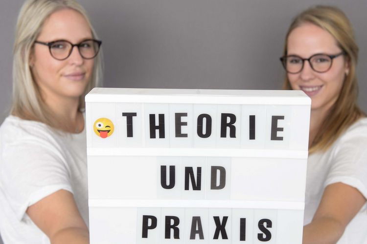Azubis mit Schild "Theorie und Praxis" in der Pflegeausbildung im Klinikum Saarbrücken