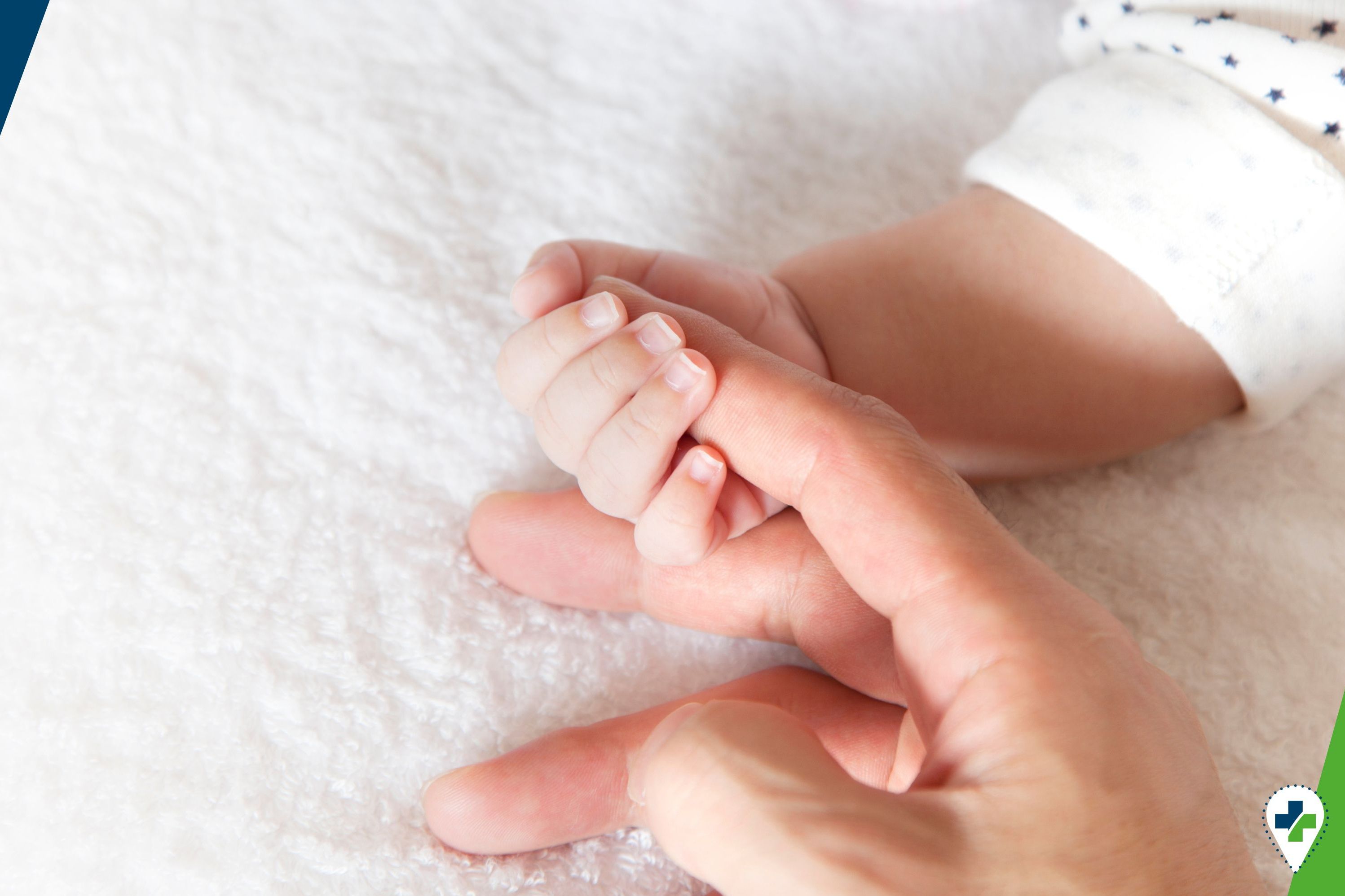 Die Hand des Babys greift nach dem Finger eines Erwachsenen.