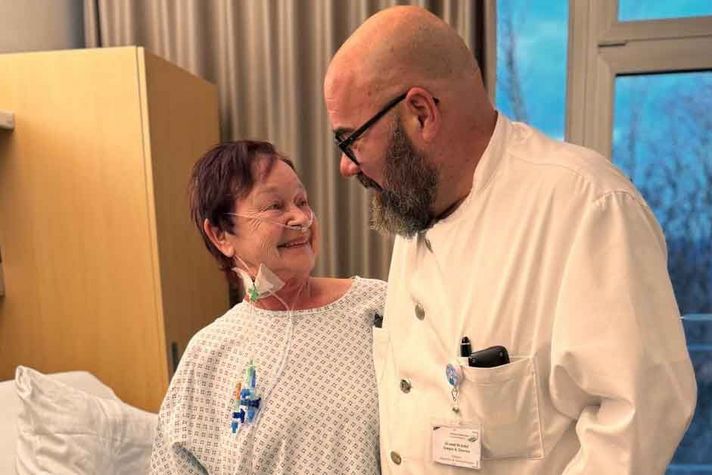 Patientin Roswitha Puhl steht links neben Chefarzt Dr. Dr. habil Gregor Stavrou und lächelt ihn an. 