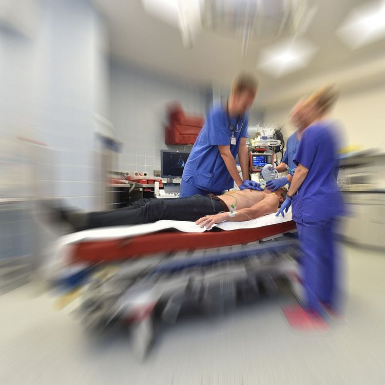 Notfallsimulation / Herzstillstand: Ärzte in der Zentralen Notaufnahme bei einer Reanimation, Teile des Bildes sind verschwommen