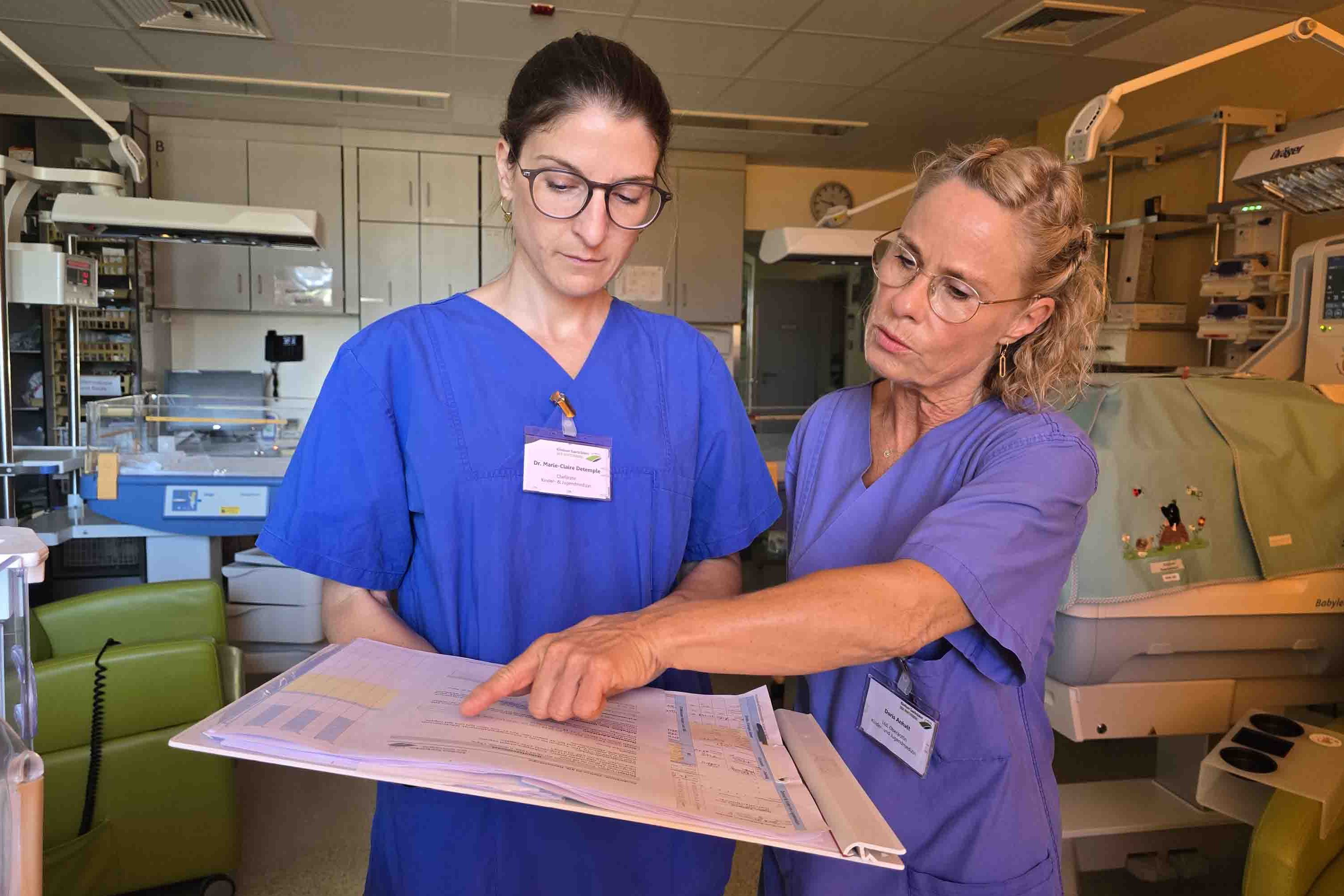 Dr. Marie-Claire Detemple und Dr. Doris Anhalt tauschen sich über die medizinischen Befunde eines neugeborenen Babys aus.