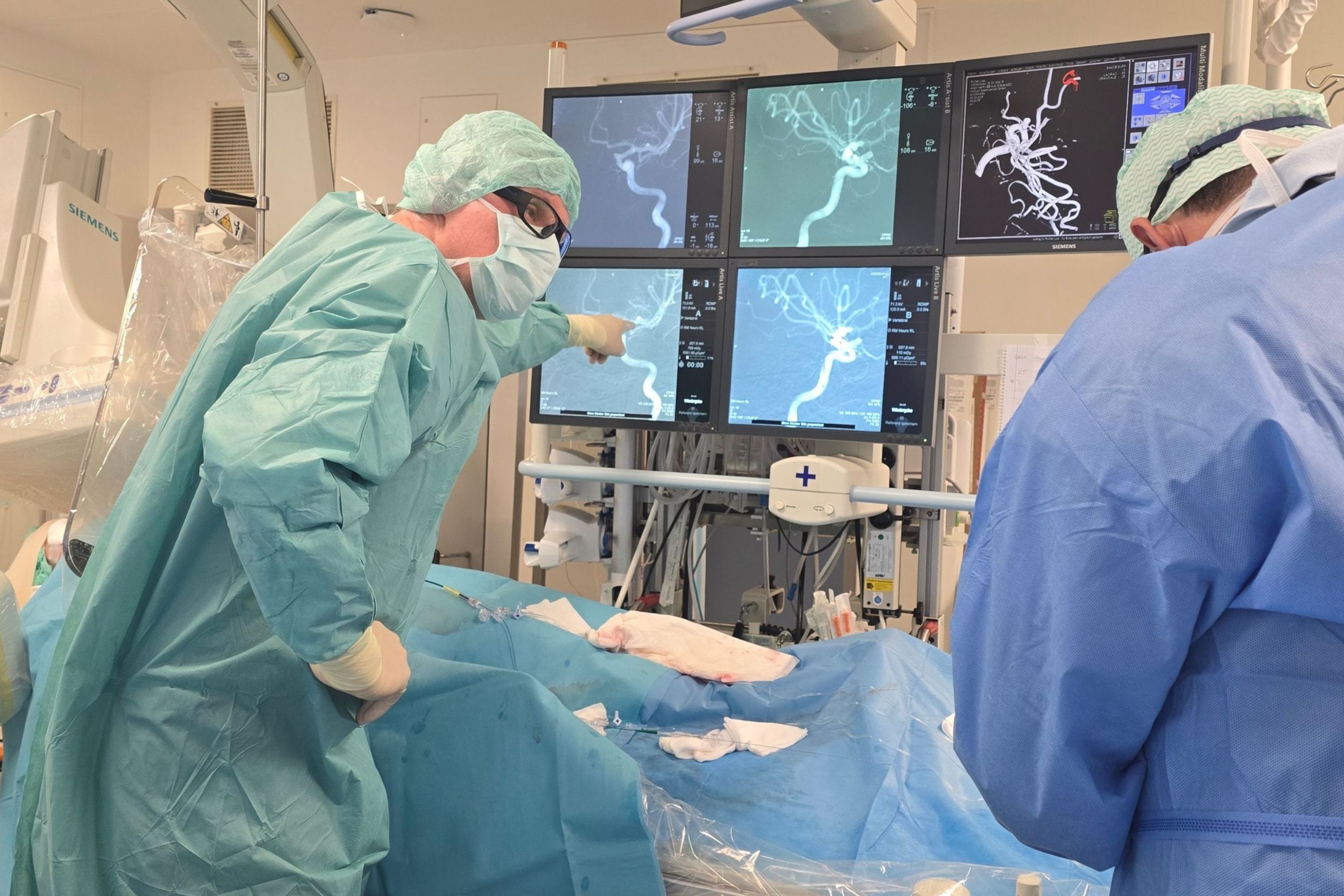 Der Neuroradiologe zeigt auf die Aufnahmen der Gefäßstruktur.