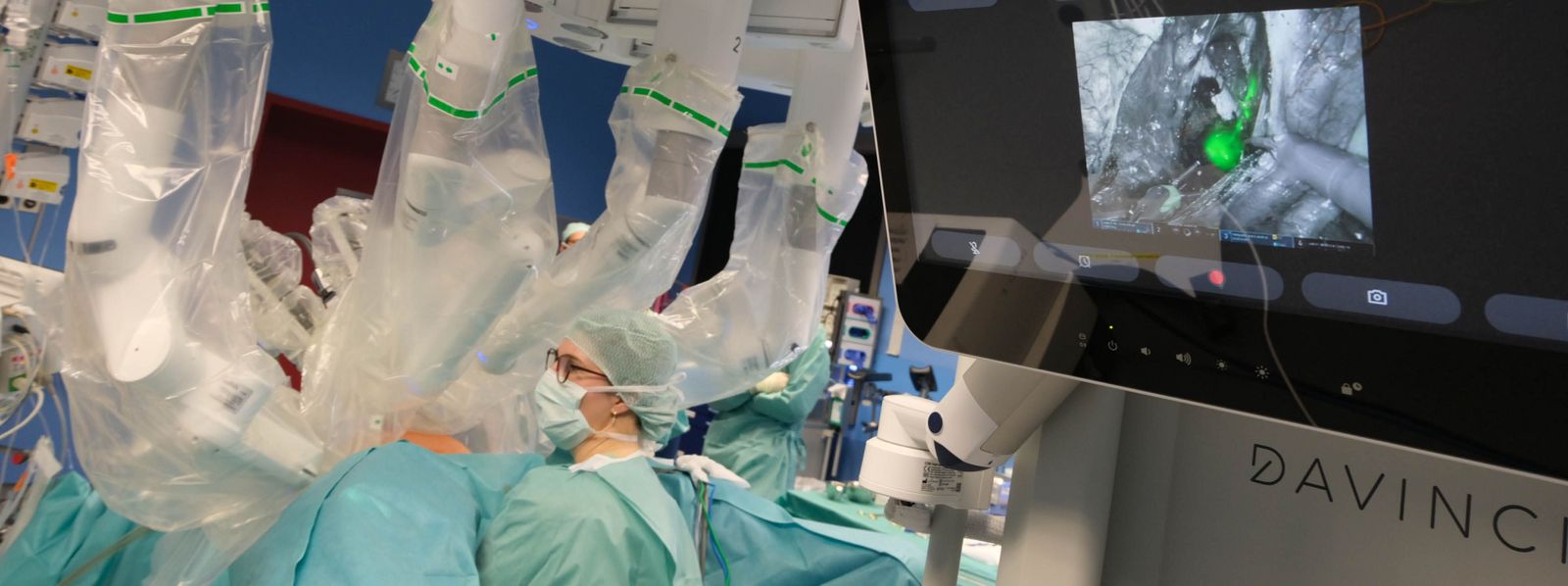 Blick auf einen Monitor, bei dem organisches Gewebe grün hervorgehoben ist, unscharf im Hintergrund: gynäkologische Operation mit dem DaVinci-Roboter DaVinci_Gyn-OP_Slider.jpg