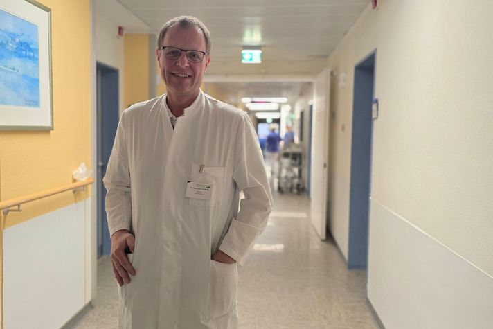 Ein Chefarzt steht in einem Krankenhausflur.