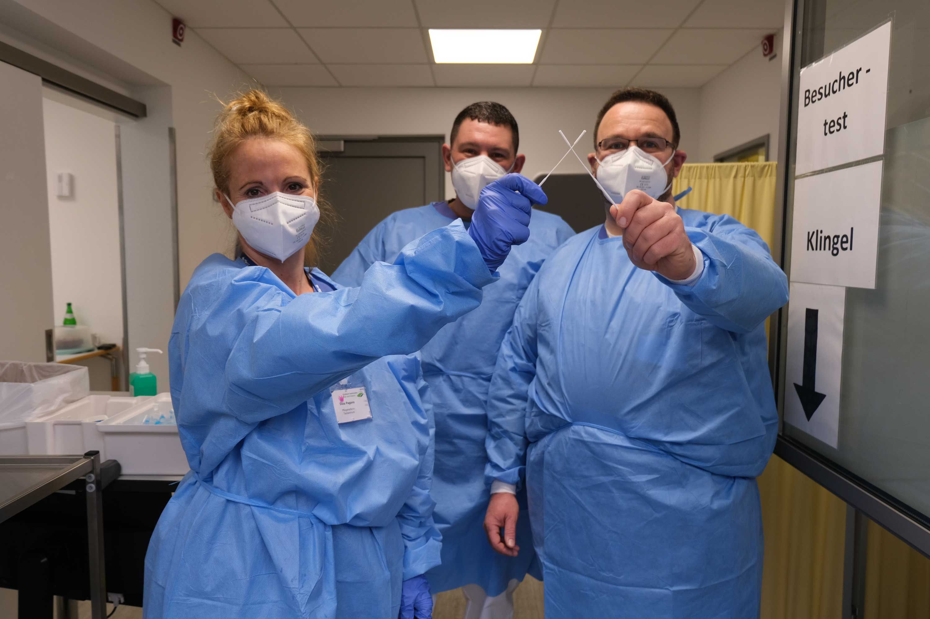 Das Bild zeigt eine Mitarbeiterin und zwei Mitarbeiter des Klinikums Saarbrücken in Schutzkleidung und mit Teststäbchen. Sie arbeiten im Testzentrum auf dem Winterberg. 
