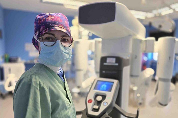 Sandra Hauser steht in einem OP-Saal und bewegt den DaVinci-Roboter durch den Raum.