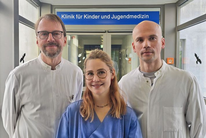 Alexander Worm, Sektionsleiter (links) und Yaroslav Isaev, Oberarzt, sind die Kinderchirurgen auf dem Winterberg. Sie stehen vor der Tür der Kinderstation, gemeinsam mit MFA Michelle Aquilino.