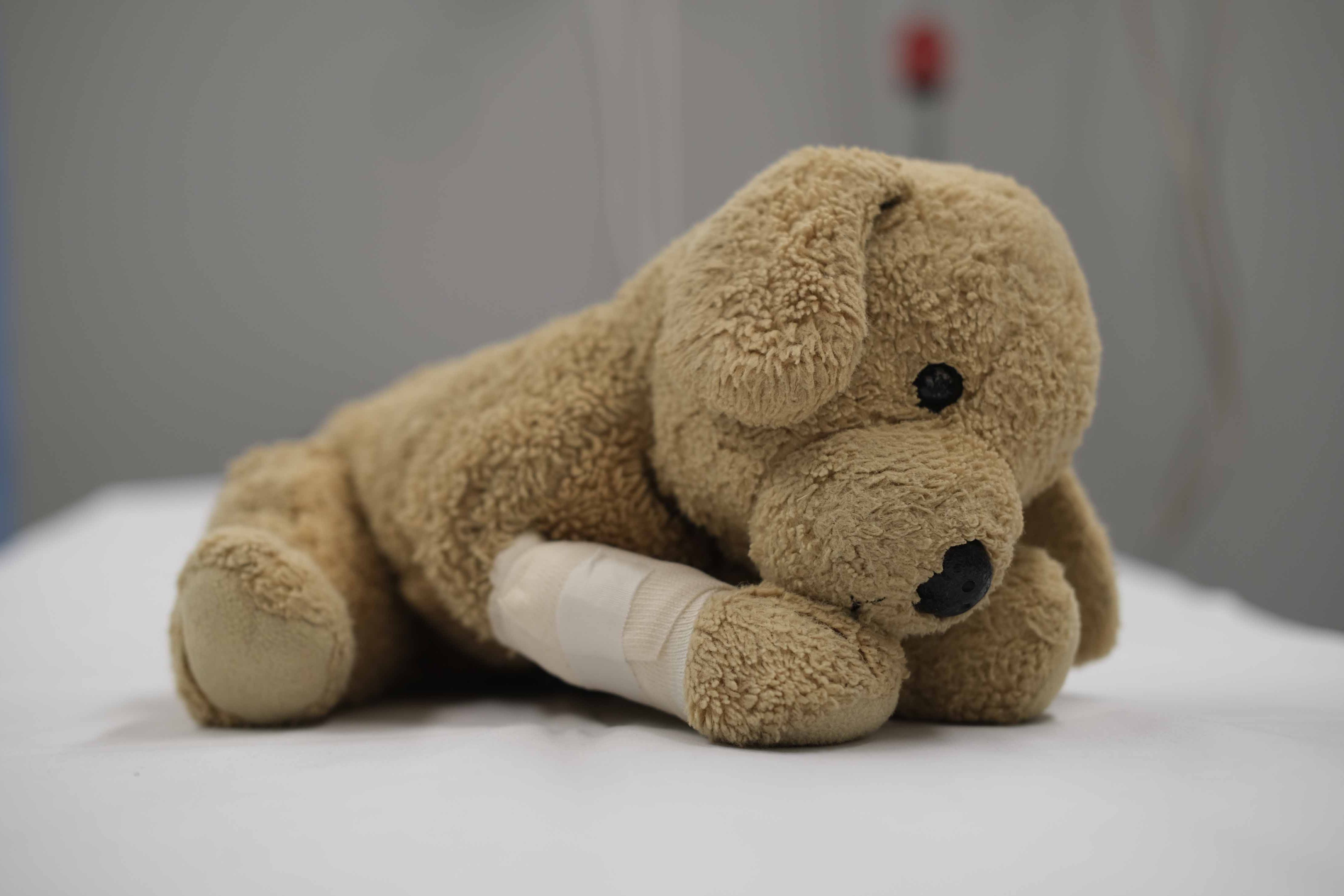 Kuscheltier mit verbundenem Beinchen auf einem Krankenbett