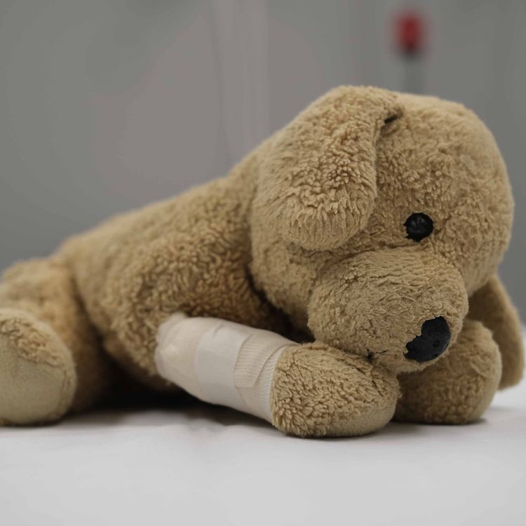 Kuscheltier mit verbundenem Beinchen auf einem Krankenbett