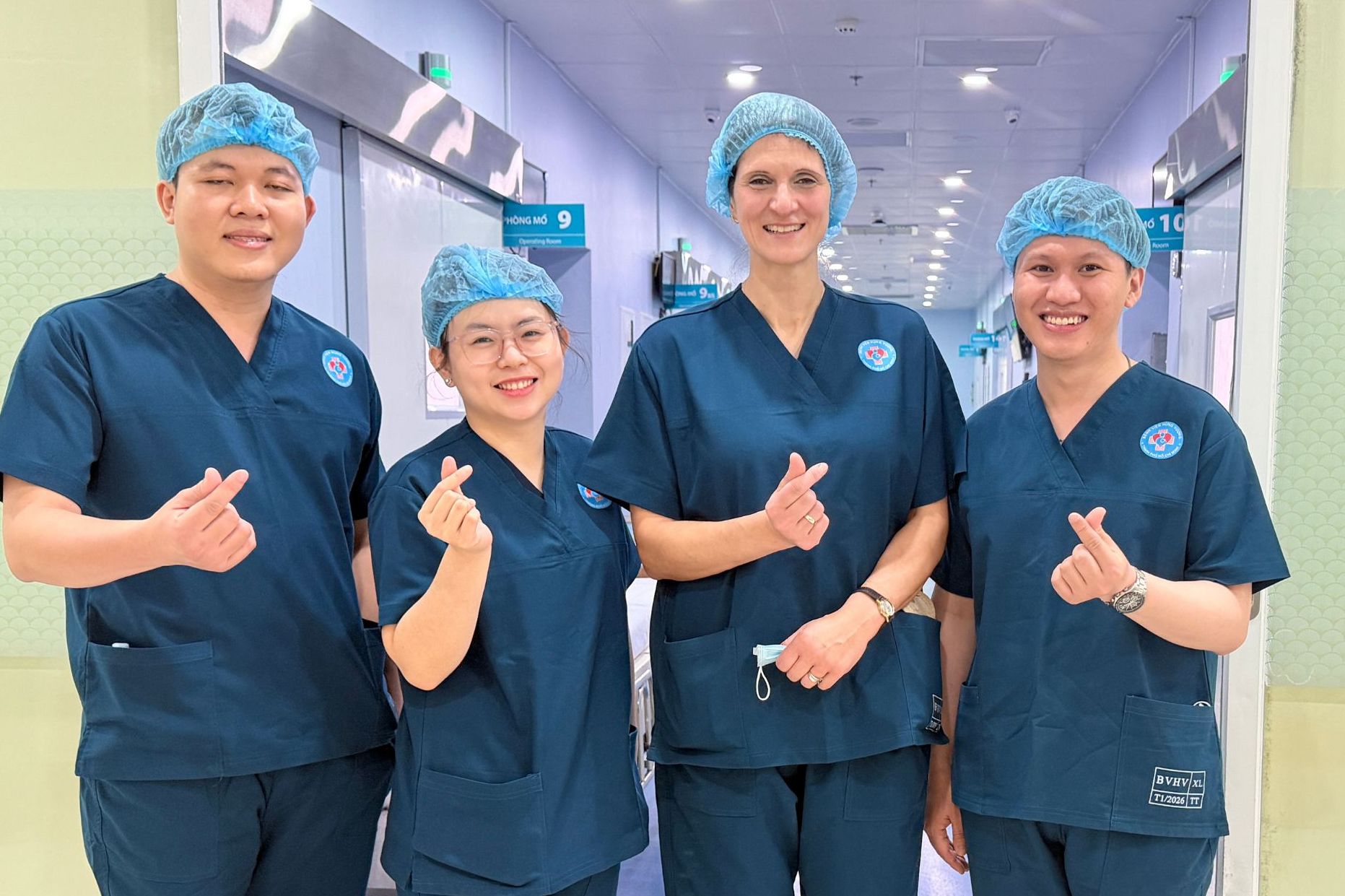 Vier Ärzte stehen vor dem OP-Trakt in Vietnam und lachen in die Kamera.