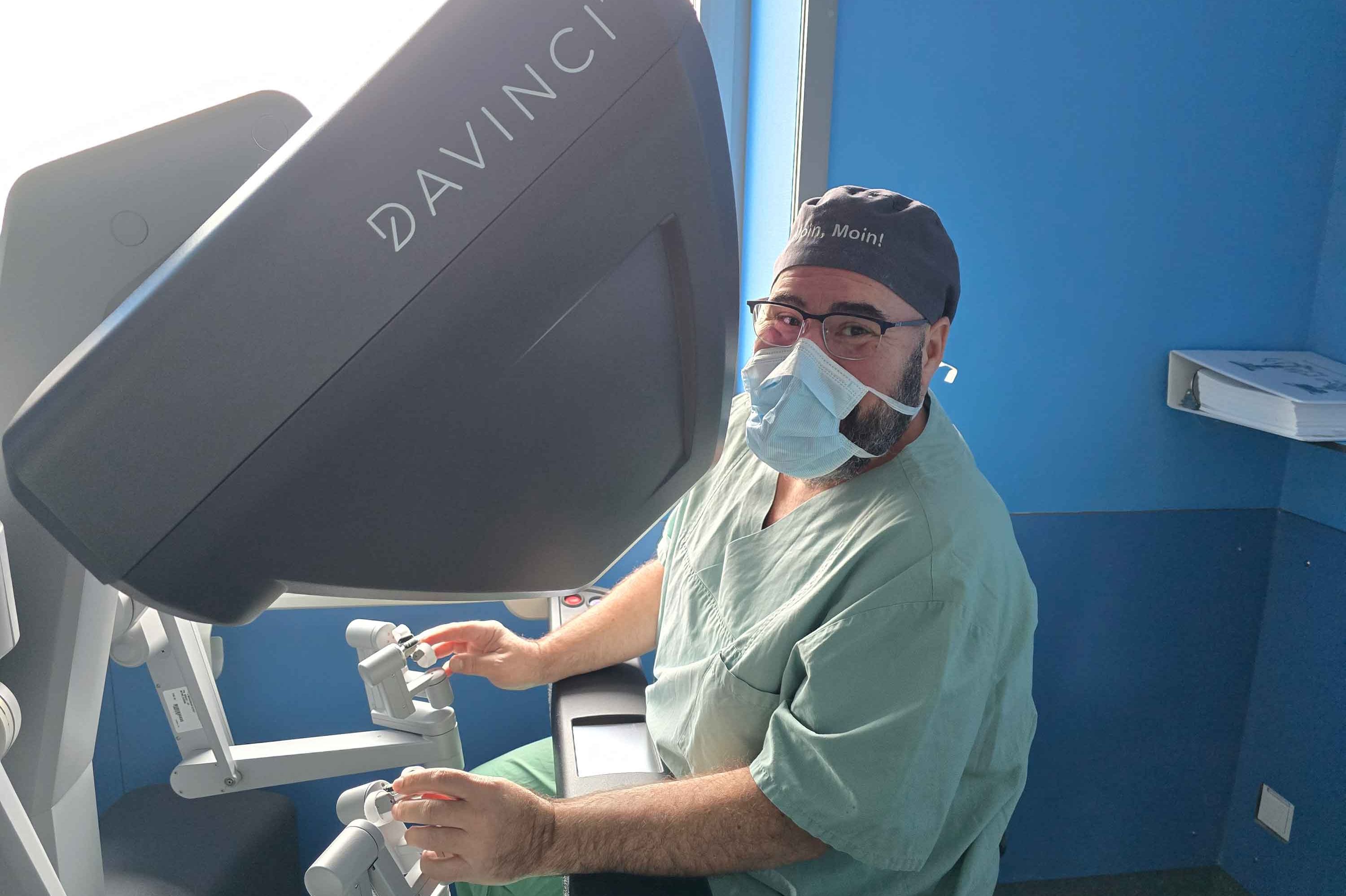 Dr. Dr. habil Gregor Stavrou sitzt an einer Konsole des Robotik-Systems DaVinci. 