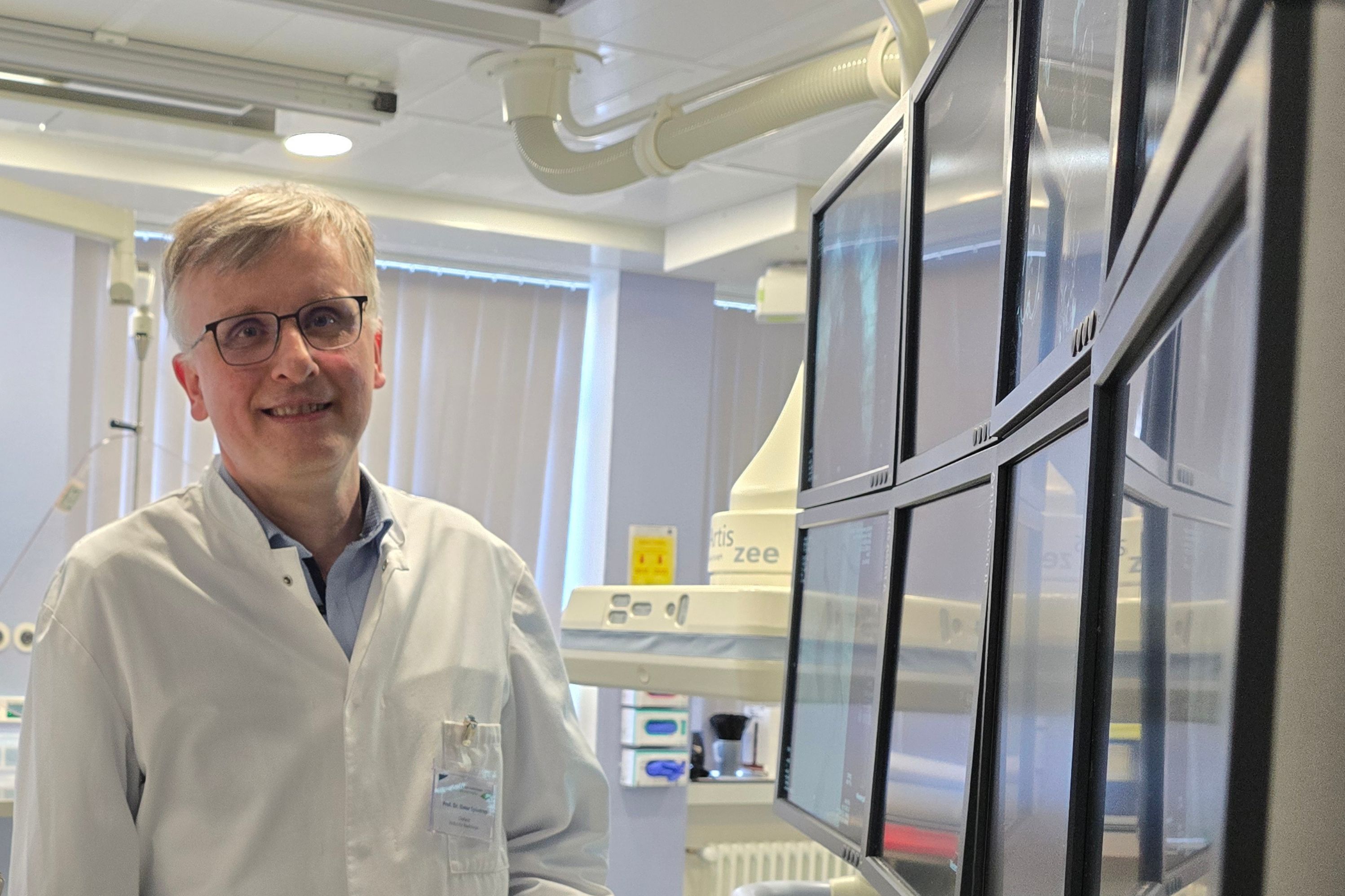 Prof. Dr. Elmar Spüntrup steht vor vielen Monitoren, die ihm die Gefäße seines Patienten zeigen.
