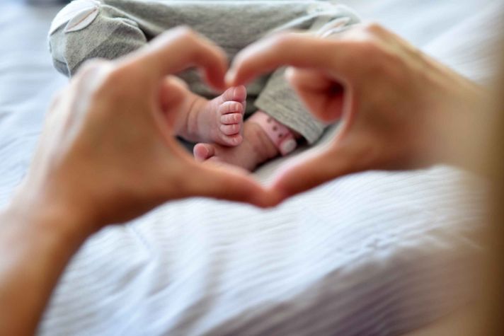 Hände bilden Herz und umrahmen Babyfüße im Klinikum Saarbrücken