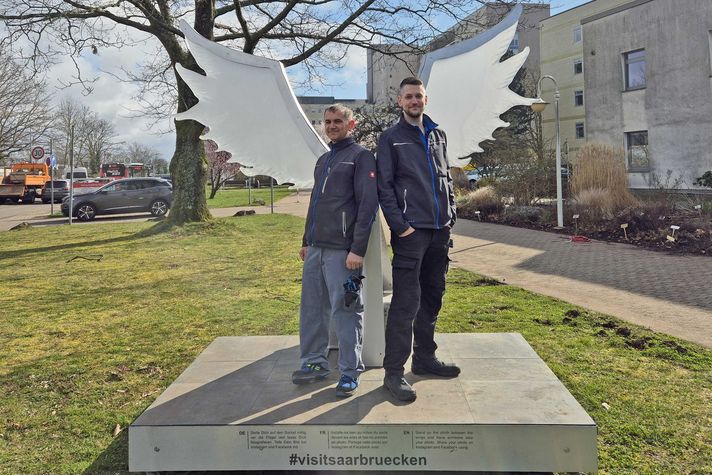 Robert und Marco aus der Technischen Abteilung des Klinikum stehen vor den Saarbrücker Flügel und lachen in die Kamera. 