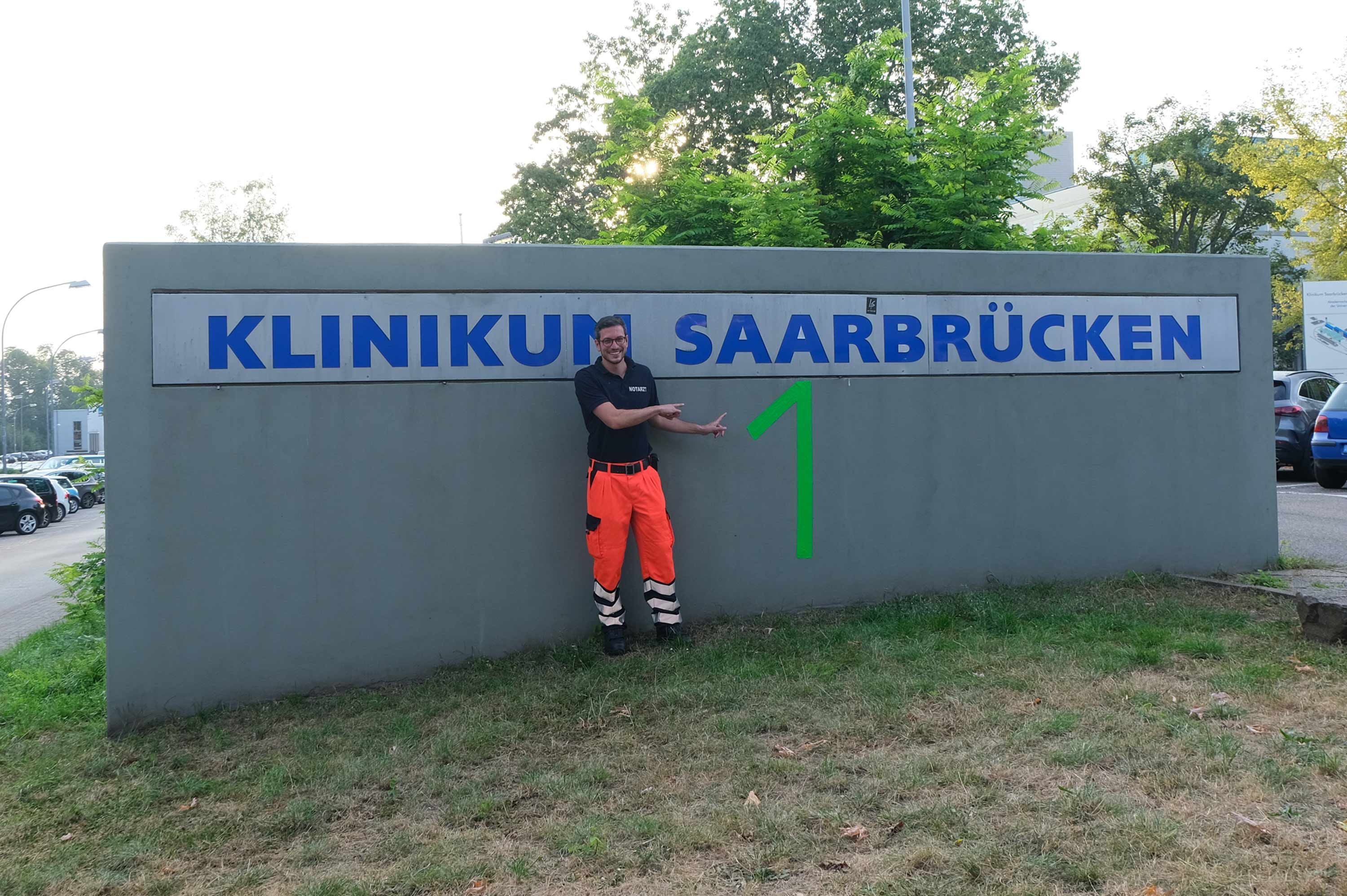 Rettungsmediziner zeigt auf die Hausnummer 1 auf dem Gelände des Klinikums Saarbrücken