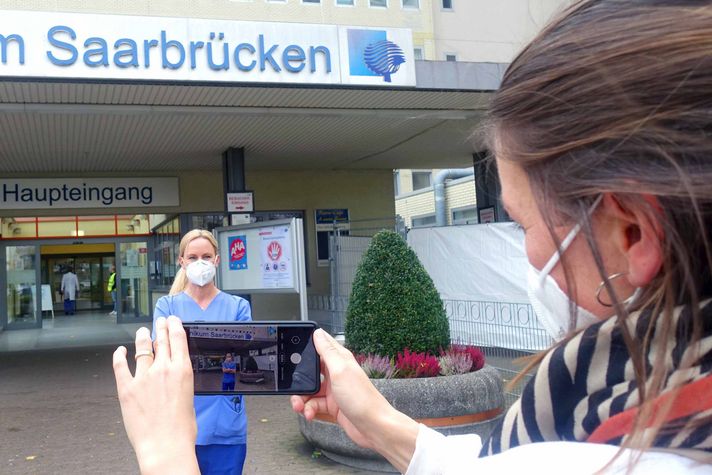 Mitarbeiterin fotografiert Pflegefachkraft vor dem Klinikum Saarbrücken