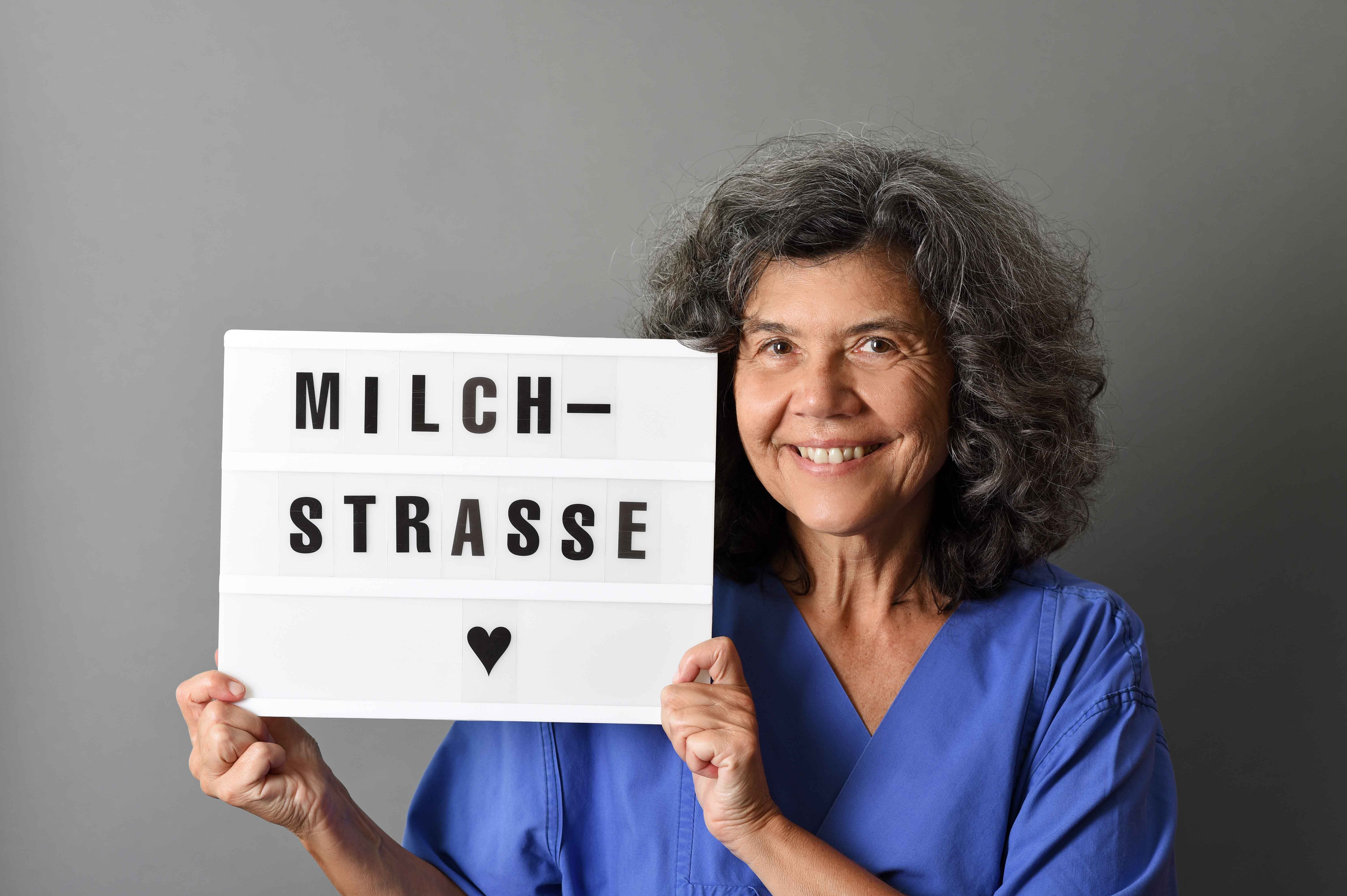 Kursleiterin Eva Vogelgesang hält eine Tafel mit dem Kurstitel "Milchstraße" in der Hand