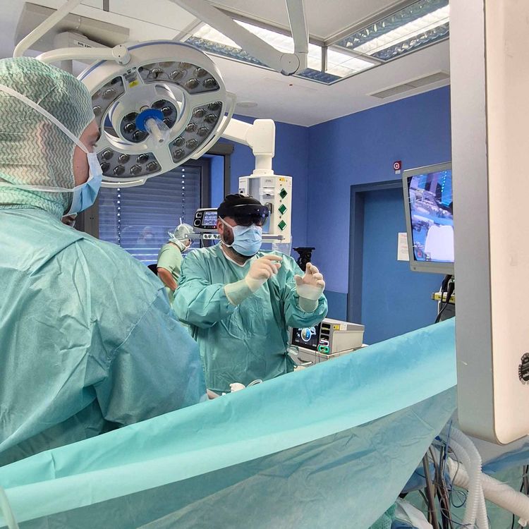 Operateur mit AR-Brille als Assistenzsystem im OP, über die Hände hat er Zugriff auf ein 3-D-Modell der Organe