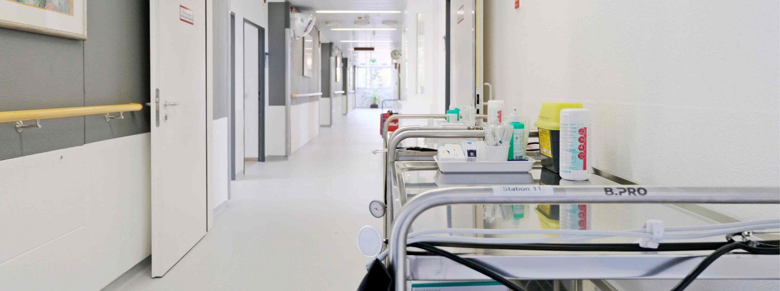 Ein Krankenhausflur mit einem Stationswagen im Vordergrund des Fotos Slider_Patienten_und_Besucher.jpg