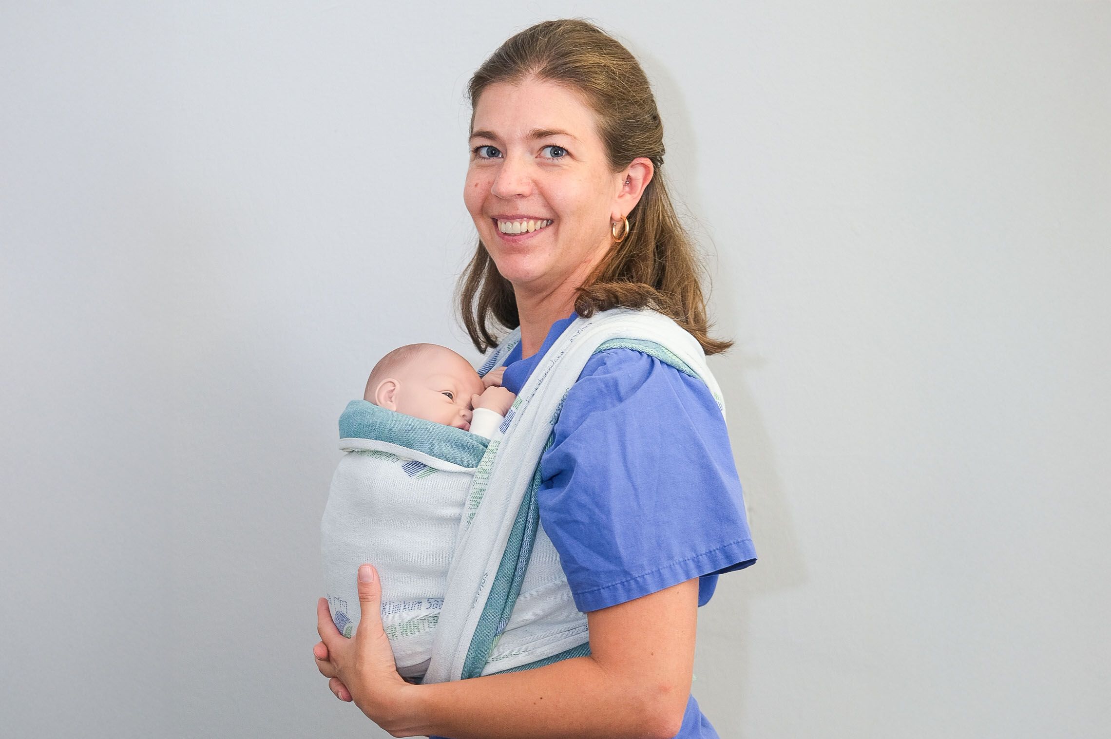 IBCLC Simone Zimmer trägt im Klinikum Saarbrücken eine Puppe im Tragetuch, um das richtige Binden zu erklären