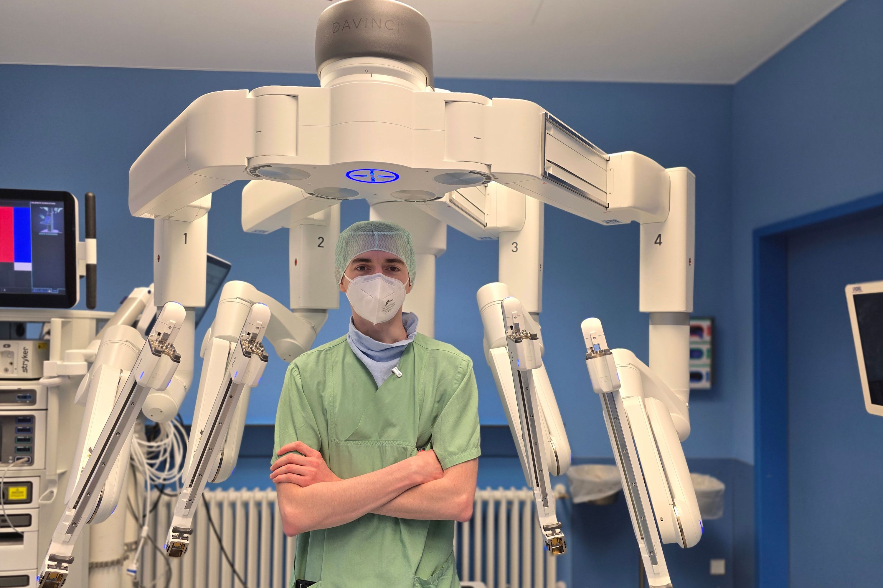OTA Tim Ruth steht zwischen den Roboterarmen des Operationssystems da Vinci. 
