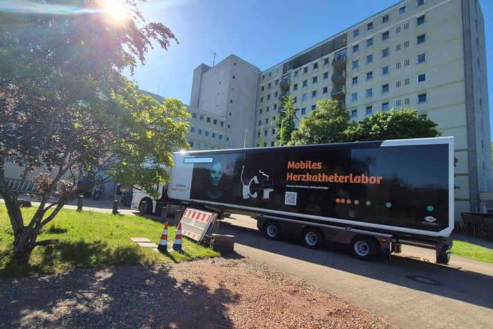 Man sieht einen großen LKW, der vor dem Klinikgebäude rangiert.