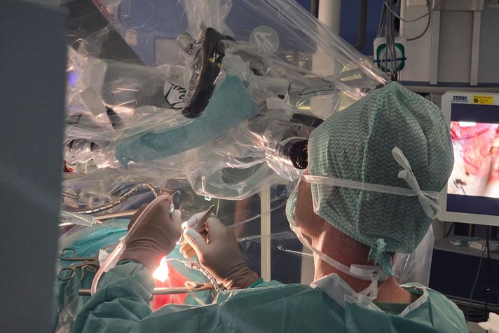 Ein Neurochirurg schaut durchs Mikroskop auf den Operationsbereich.
