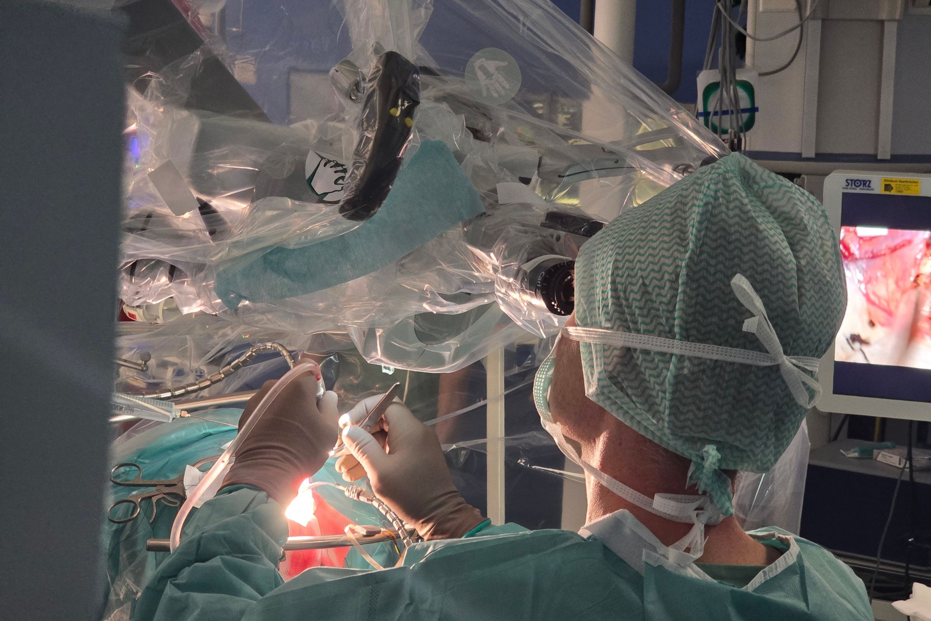 Ein Neurochirurg schaut durchs Mikroskop auf den Operationsbereich.