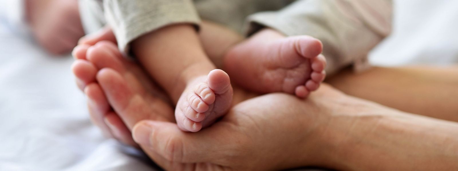Eine Hand hält die Füße eines Neugeborenen auf einem Krankenbett Kinderklinik_Babyfuesse_Slider.jpg