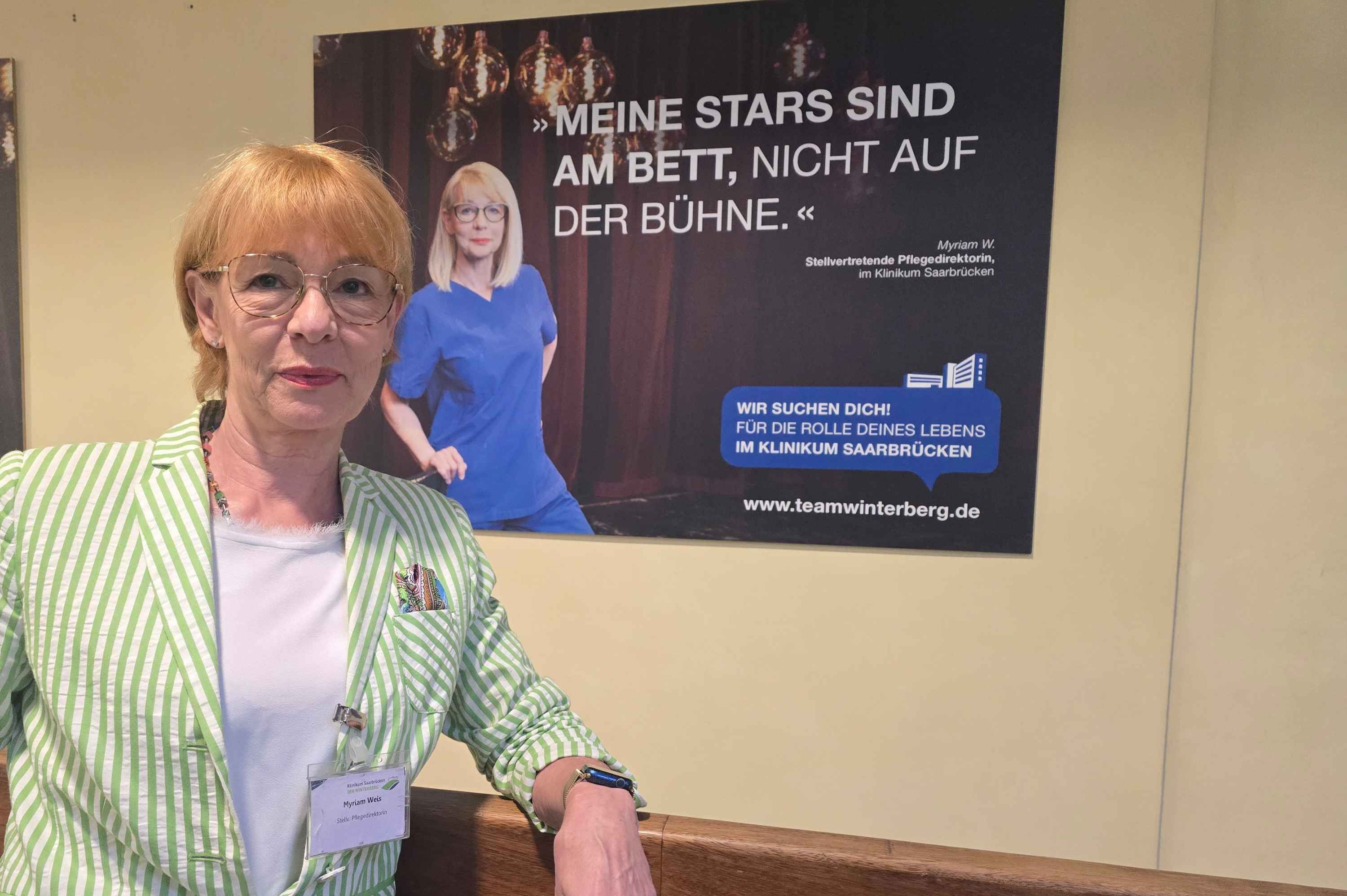 Myriam Weis vor einem Plakat, das sie selbst zeigt.