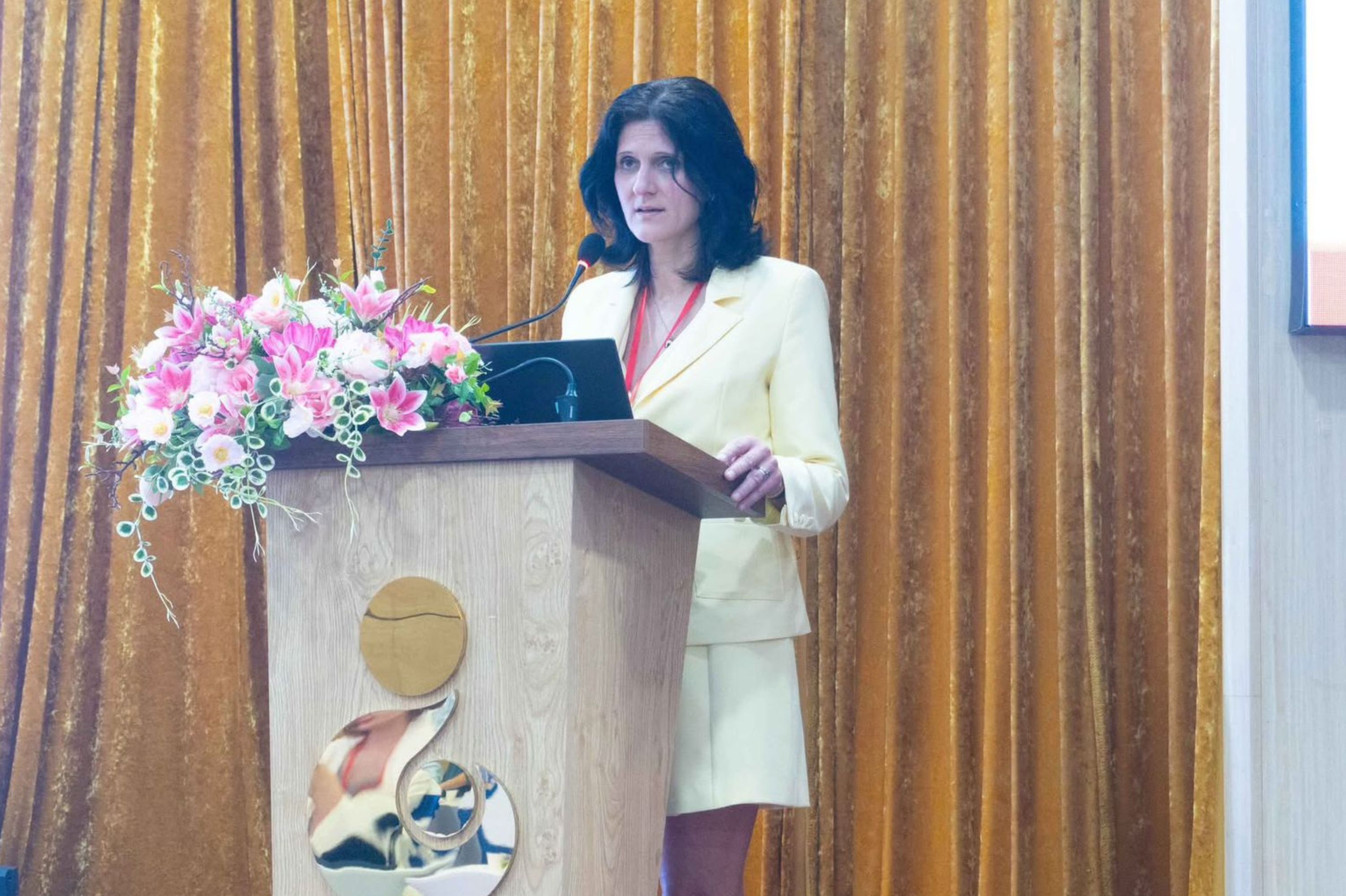 Eine Frau steht an einem Rednerpult und hält eine Rede.