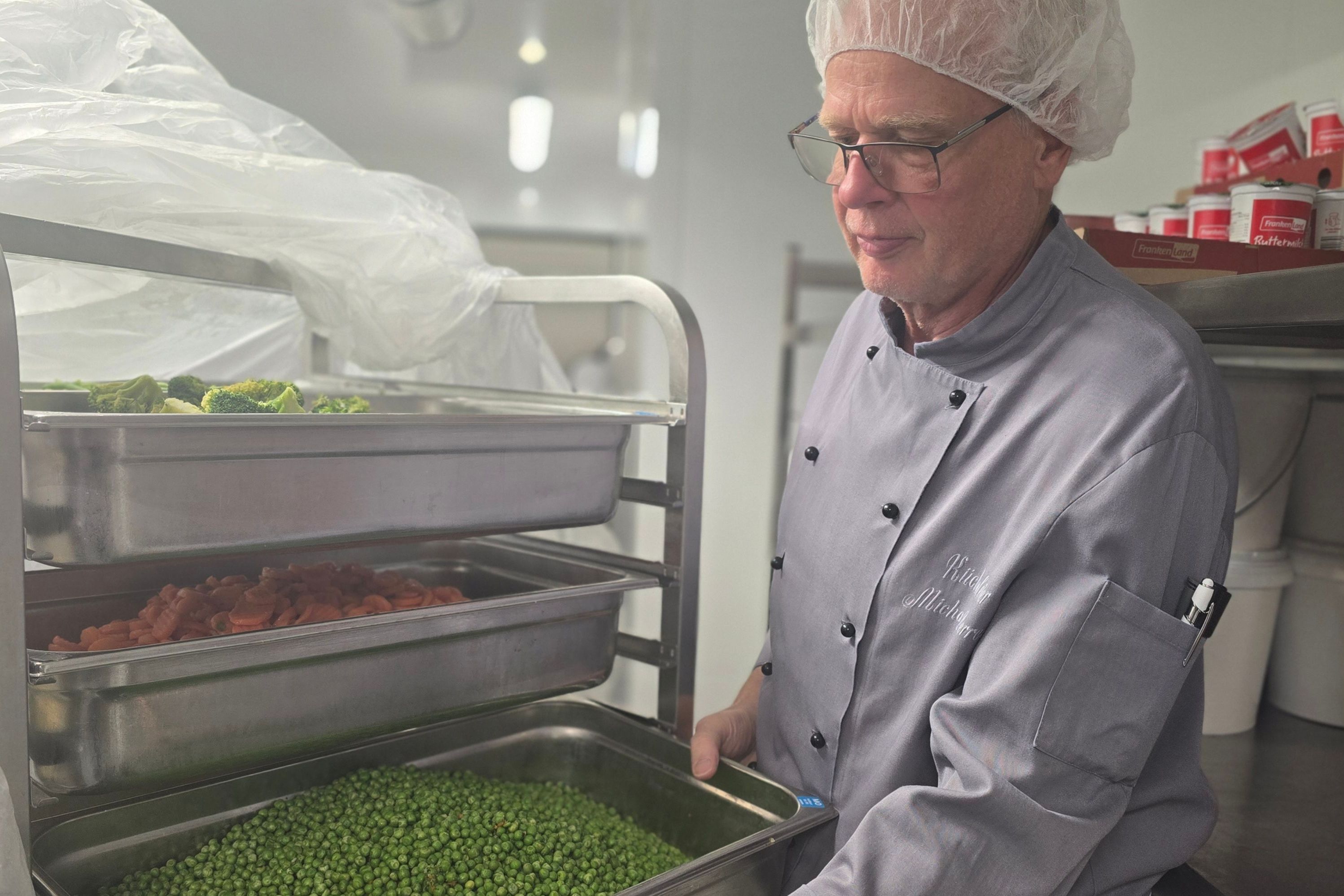 Der Küchenchef zeigt die vor Grün strotzenden Erbsen fürs Mittagessen.
