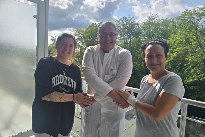 Das Foto zeigt Thoraxchirurg Alexander Gamrekeli, wie er über Kreuz zwei Patientinnen, die rechts und links von ihm stehen, die Hände gibt. Er hat beide operiert, weil sie übermäßig an den Händen geschwitzt haben. Die Zeiten sind jetzt vorbei.