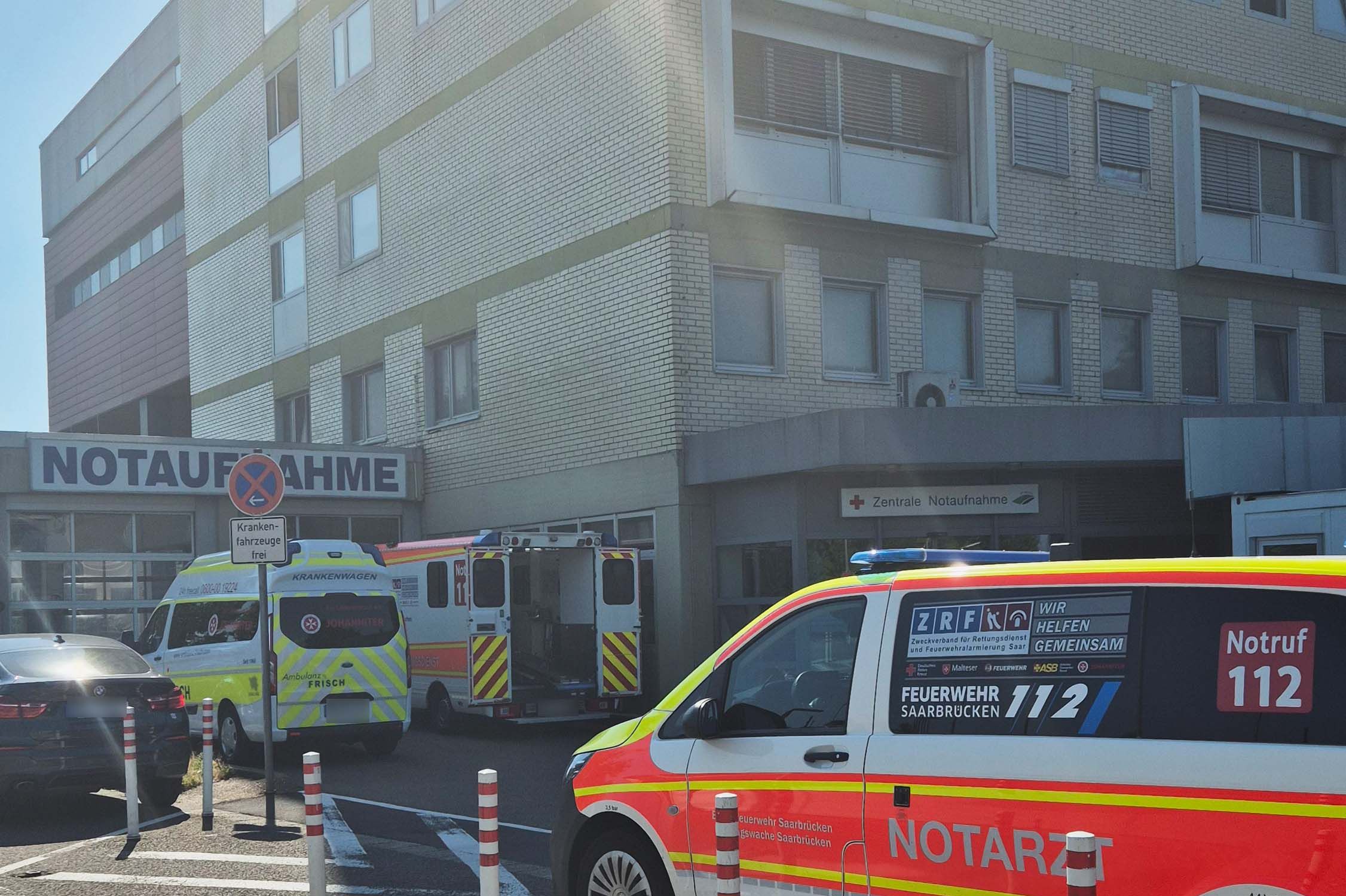 Blick auf die Notaufnahme vom Klinikum Saarbrücken im Sommer vor der mehrere Krankenwagen und ein Notarzt-Einsatzfahrzeug stehen