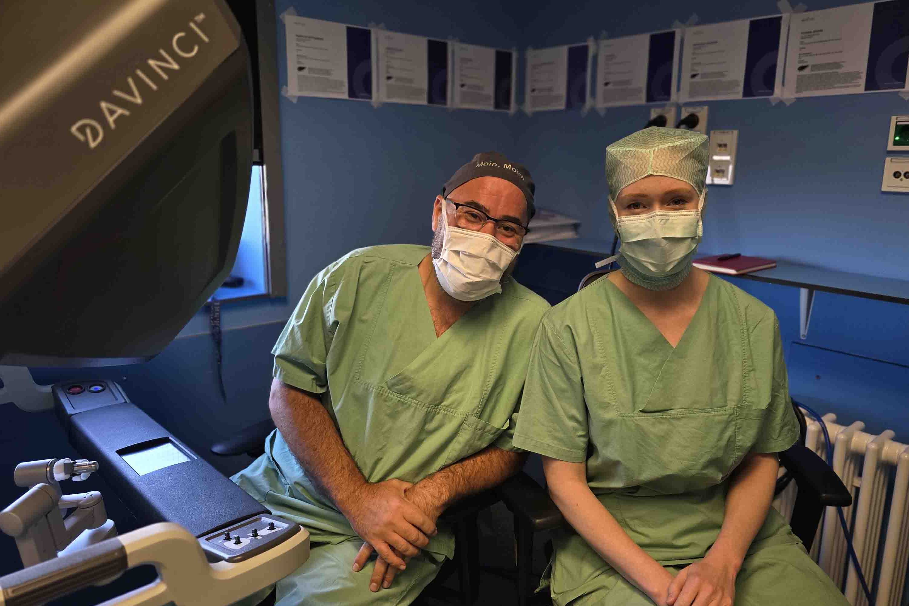 Chefarzt Dr. Dr. habil Gregor Stavrou und die Stipendiatin Dr. Svenja Sliwinski an den beiden Konsolen des OP-Roboters.