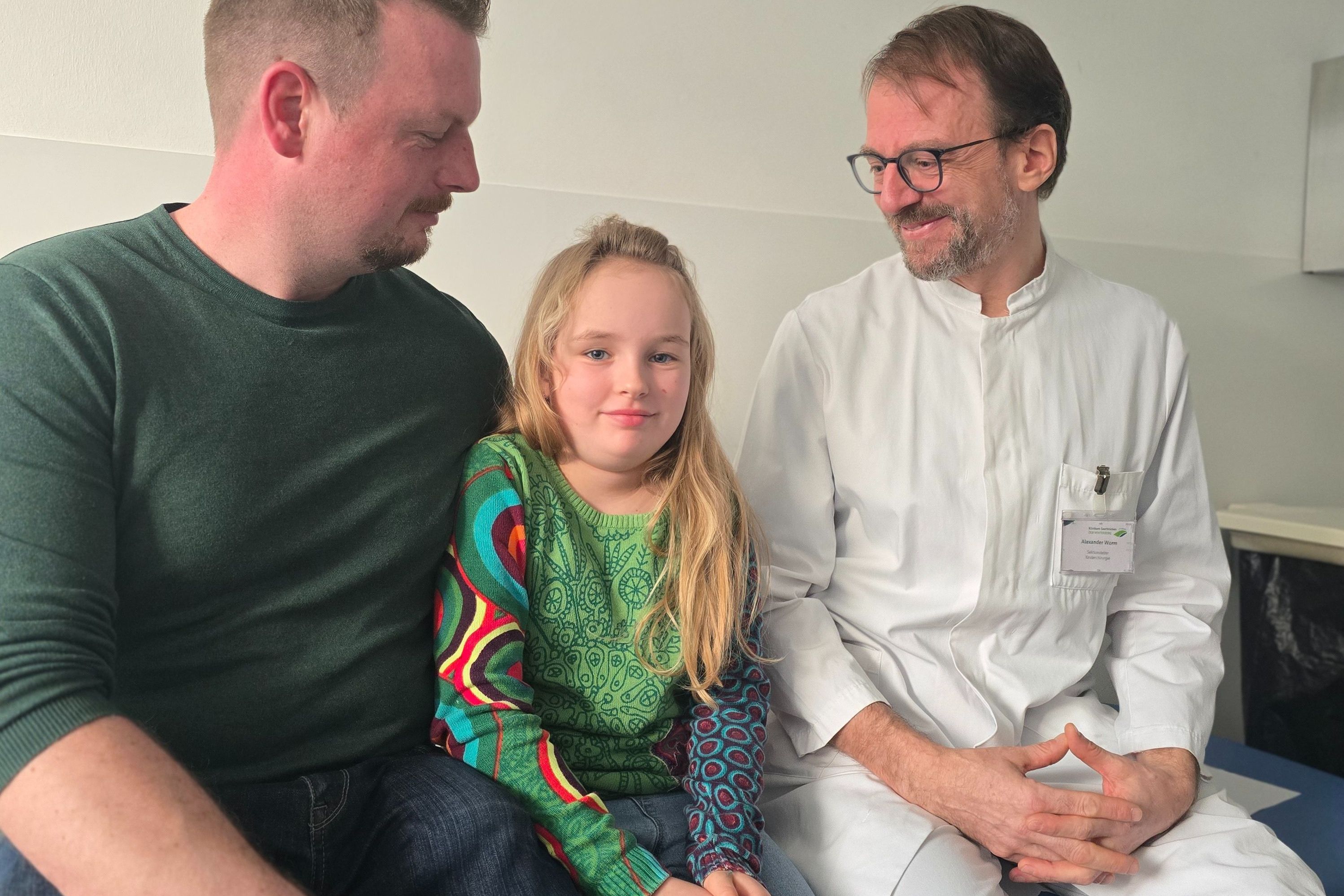 Papa Sascha Rung mit Tochter Melina und dem Sektionsleiter der Kinder- und Jugendchirurgie Alexander Worm.