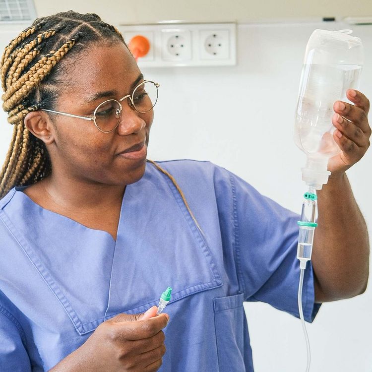 Auf dem Foto ist eine Auszubildende, die eine Infusion in der Hand hält
