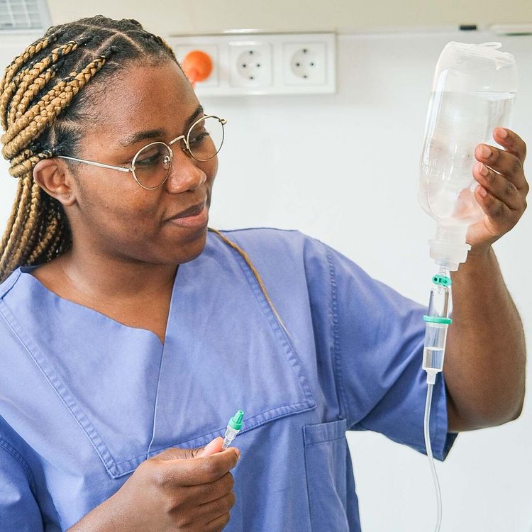 Auf dem Foto ist eine Auszubildende, die eine Infusion in der Hand hält