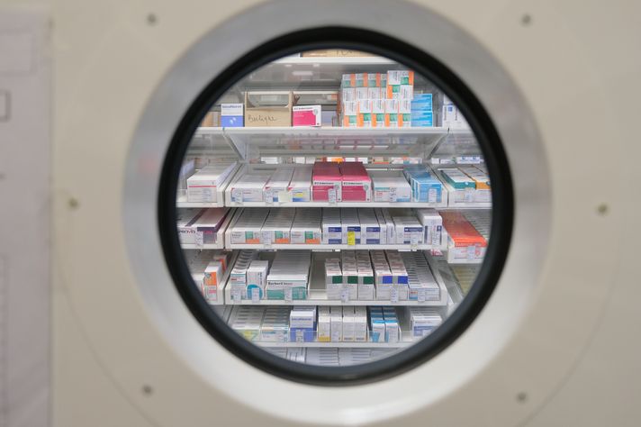 Man sieht Regale der Krankenhausapotheke durch ein rundes Fenster