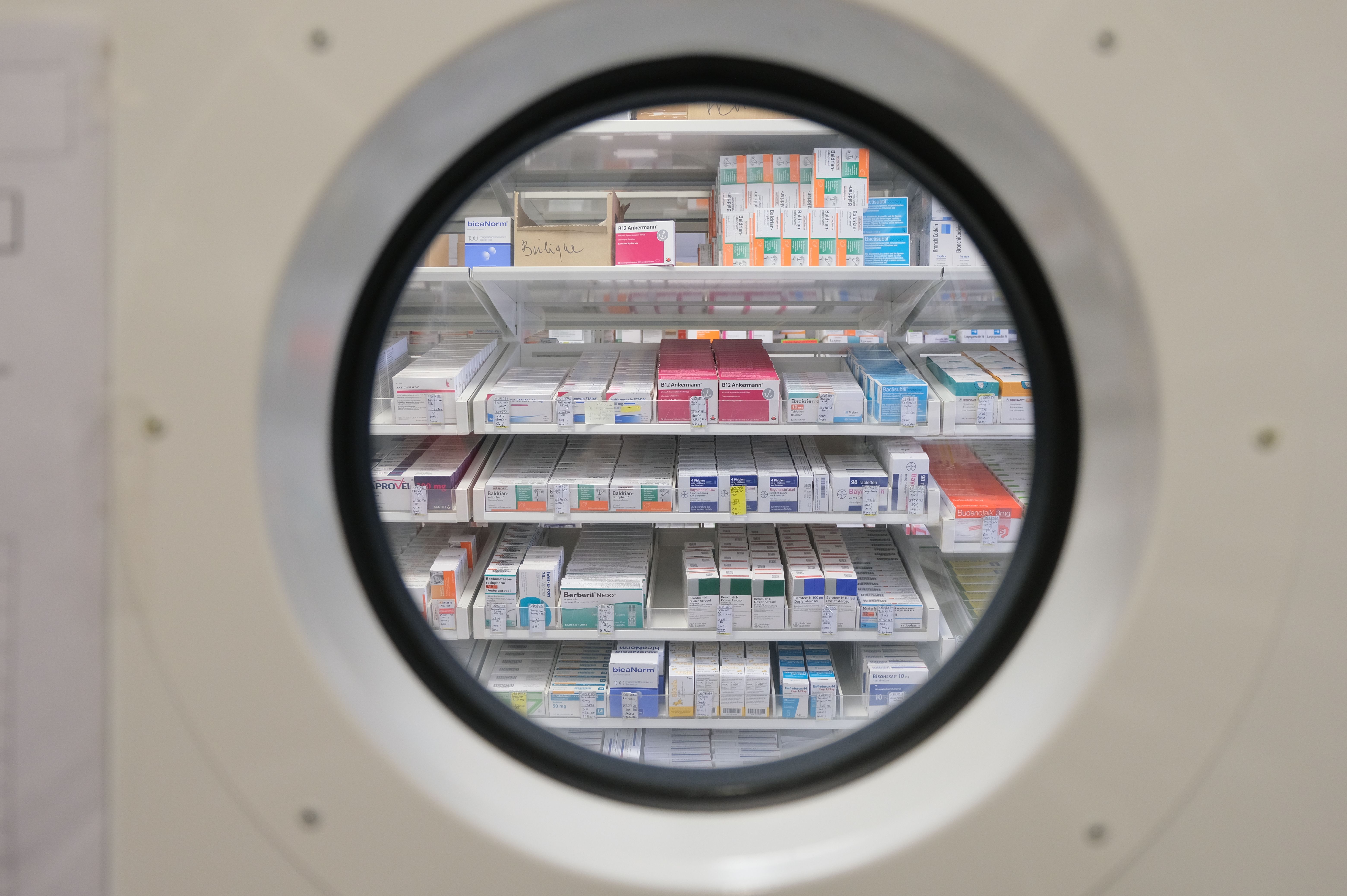 Man sieht Regale der Krankenhausapotheke durch ein rundes Fenster