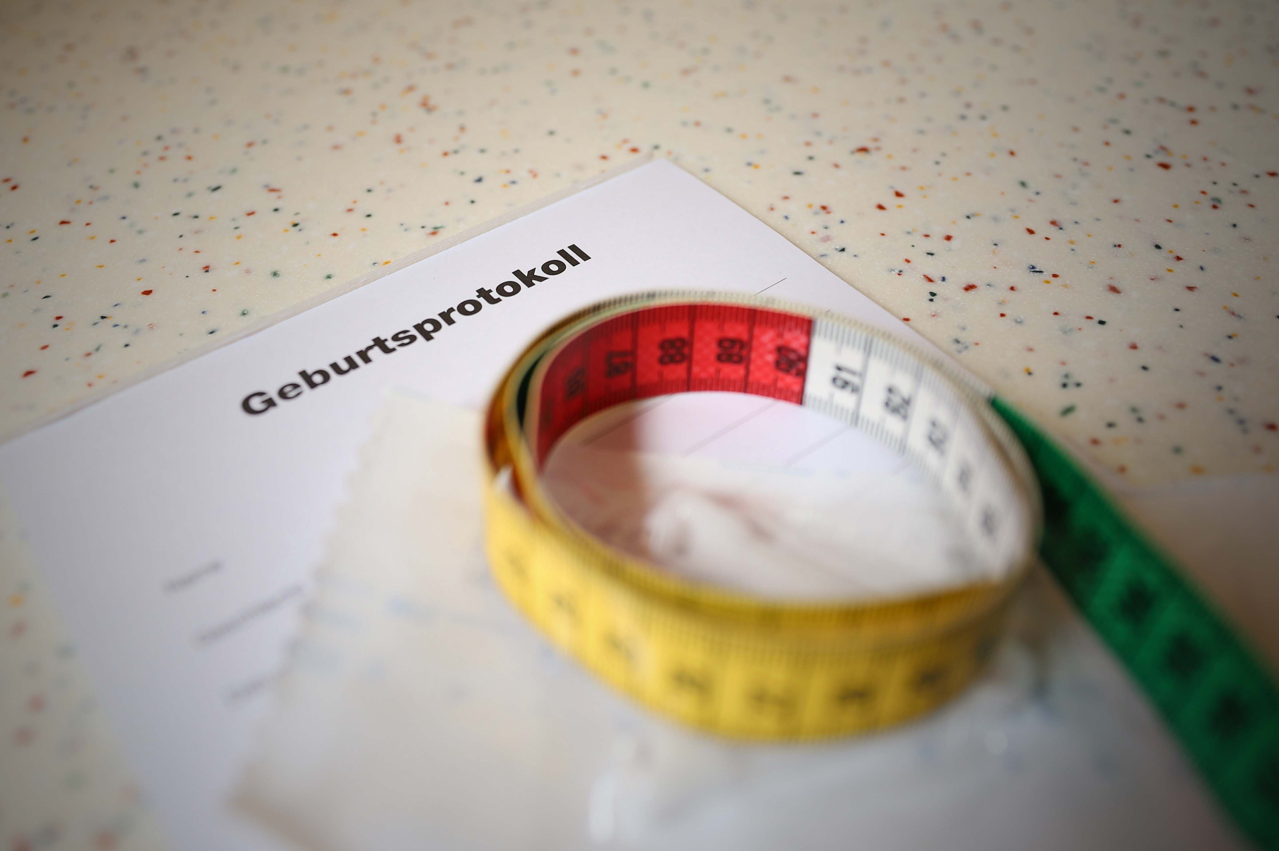 Blick auf ein leeres Geburtsprotokoll auf dem ein Maßband liegt