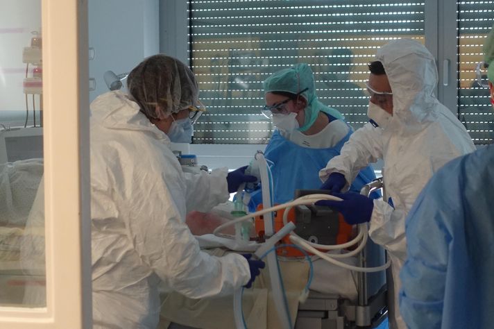 Klinisches Personal behandelt einen Corona-Patienten in persönlicher Schutzausrüstung versorgen 