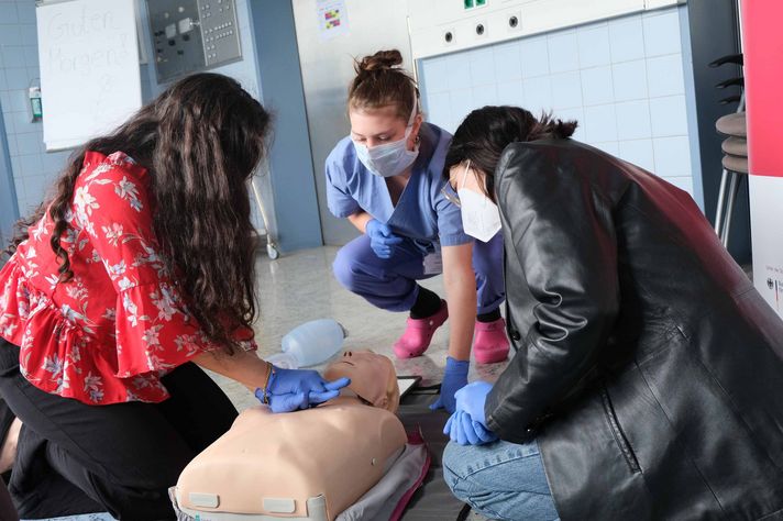 Pflegekraft zeigt Schülerinnen an einer Puppe Reanimationsmaßnahmen im Klinikum Saarbrücken
