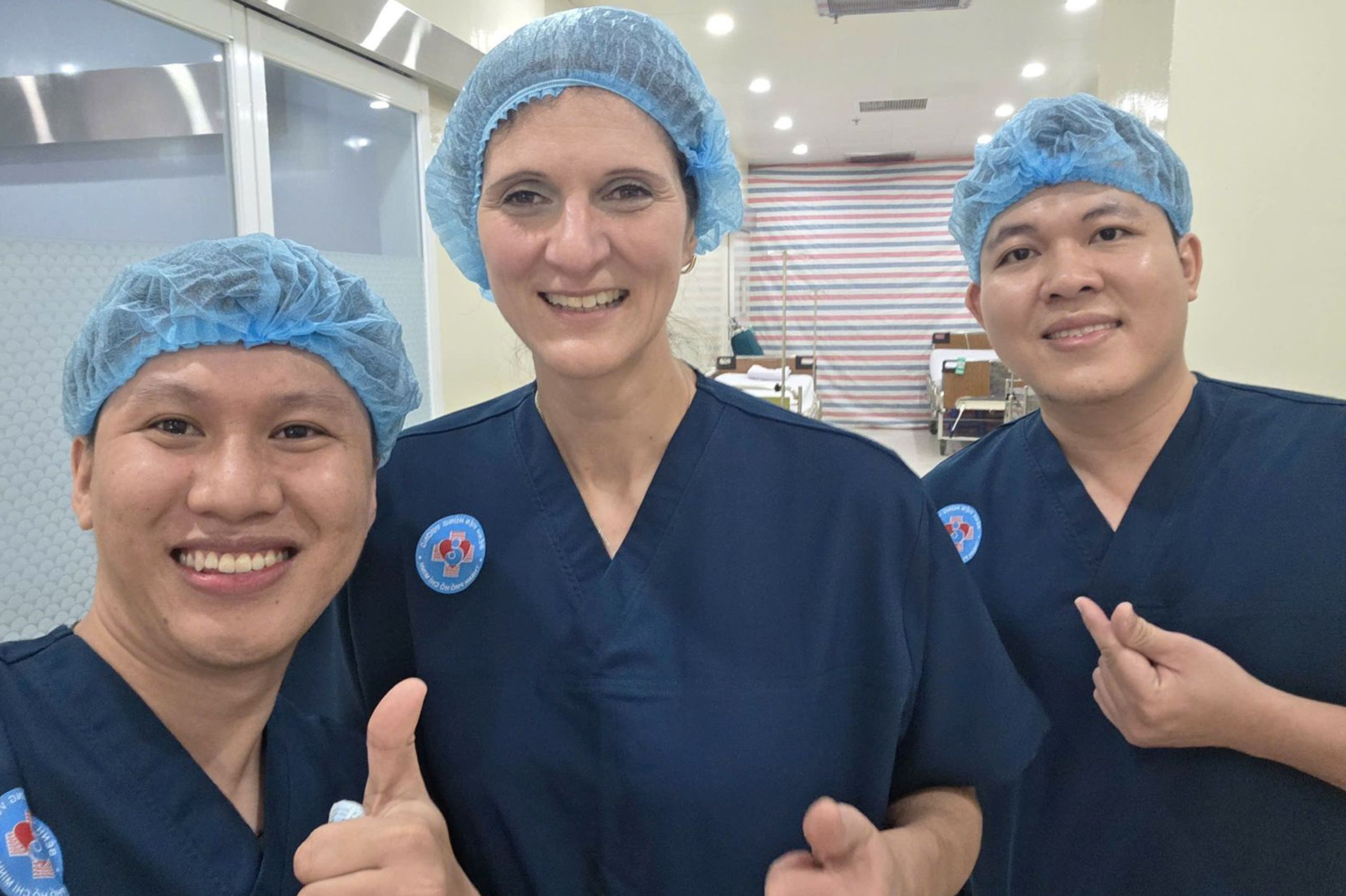 Drei Ärzte lächeln in die Kamera und zeigen "Daumen hoch".