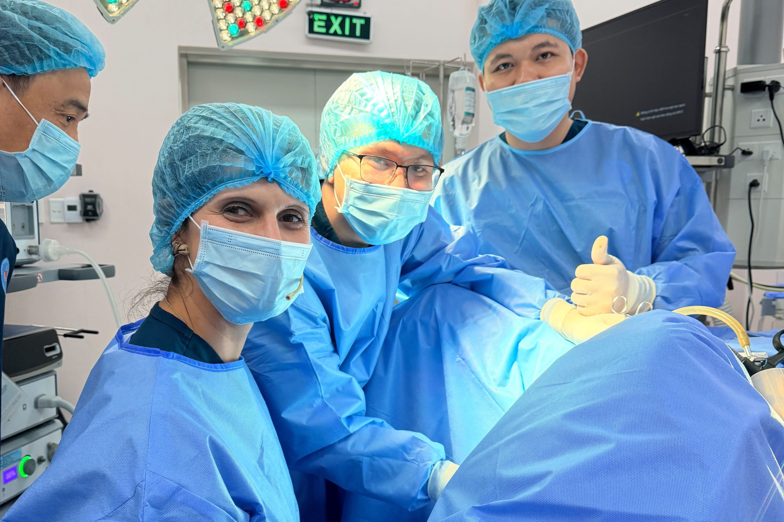 Drei Operateure am Operationstisch schauen in die Kamera.