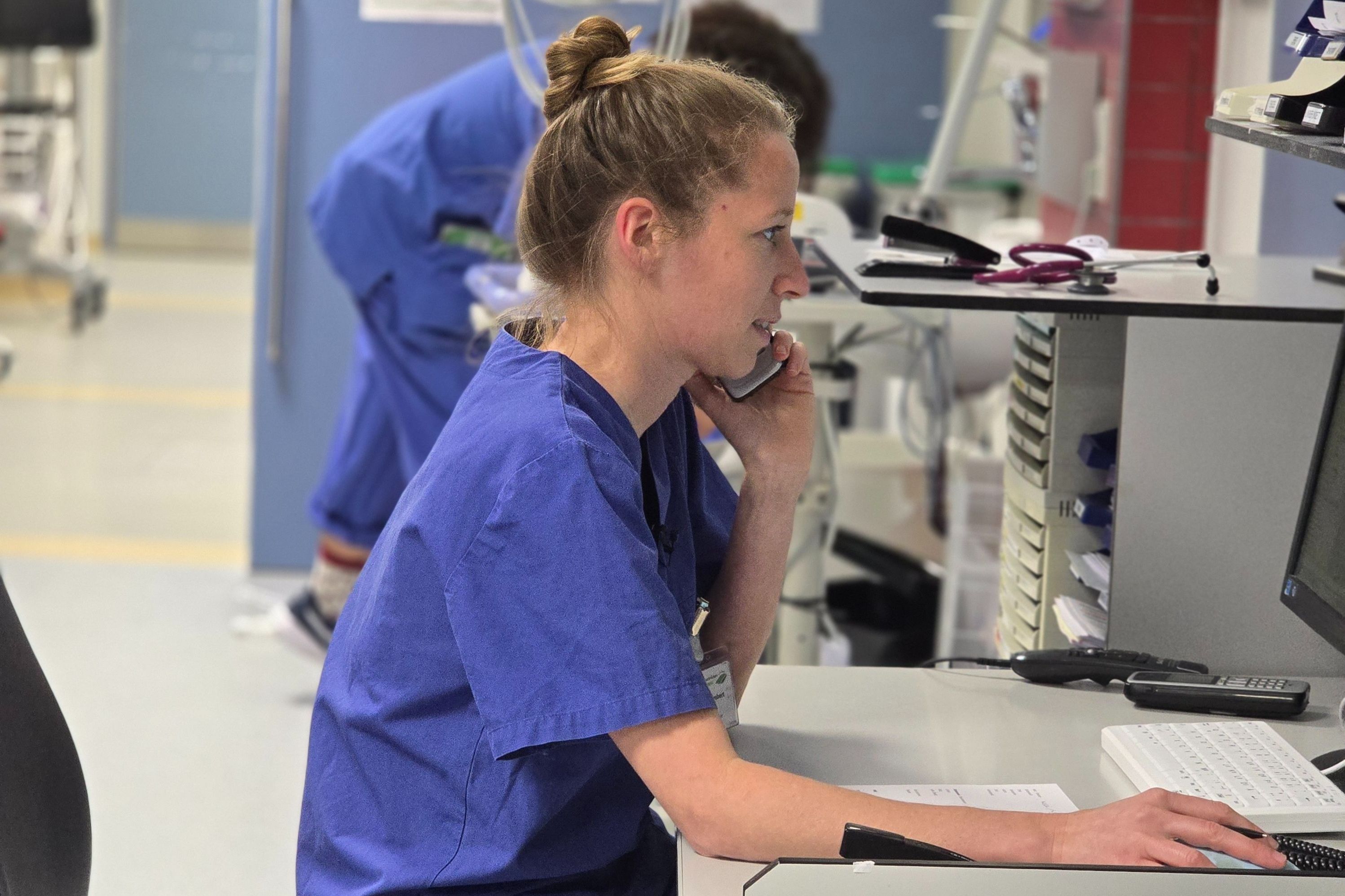 Assistenzärztin Christina Himbert telefoniert in der Notaufnahme und sitzt am Schreibtisch.