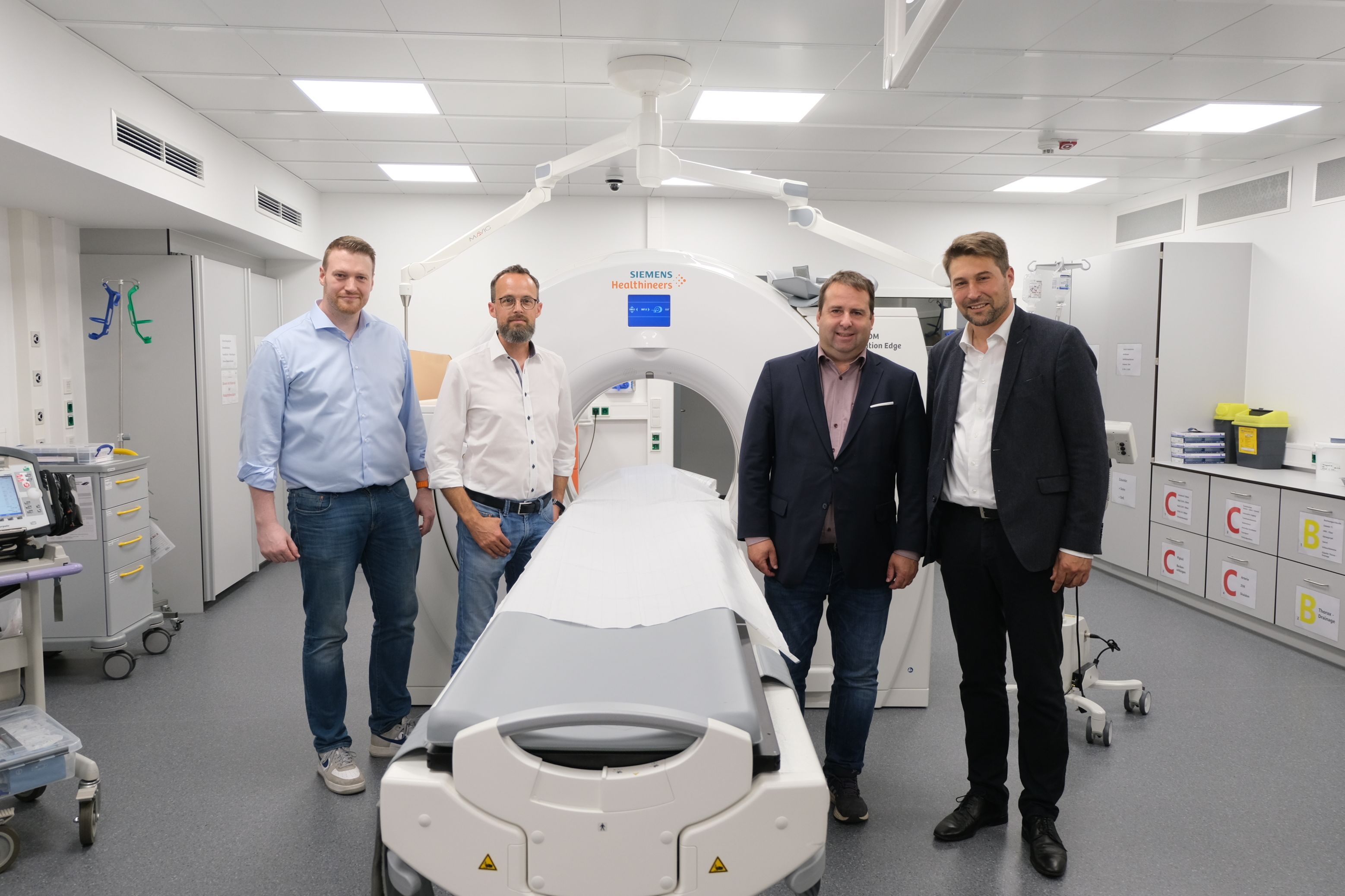 Tobias Raab (Aufsichtsratsvorsitzender), Dr. Christian Braun (Geschäftsführer und Ärztlicher Direktor Klinikum Saarbrücken), Gesundheitsminister Dr. Magnus Jung und Oberbürgermeister Uwe Conradt stehen bei der Einweihung des neuen Schockraums vor dem Computertomographen.
