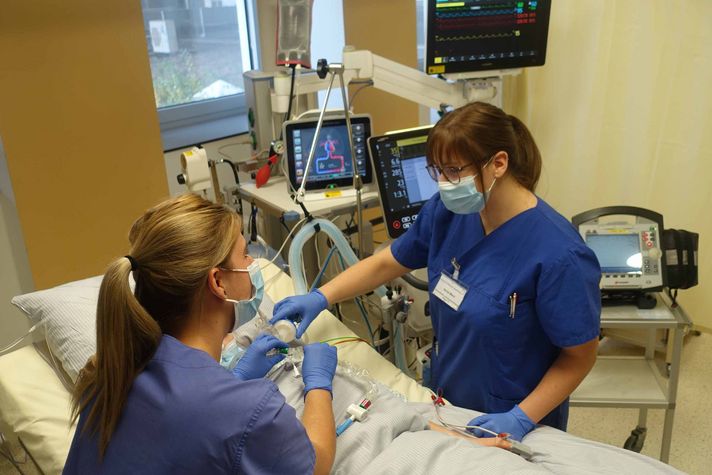Zwei Intensivpflegefachkräfte versorgen auf der Intensivstation im Klinikum Saarbrücken einen Patienten