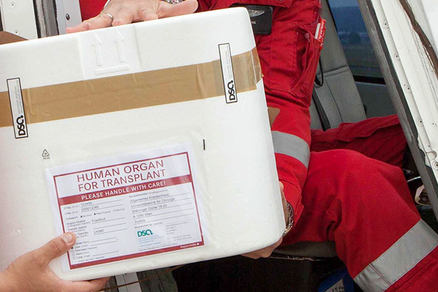 Ein Foto einer Organspendebox, im Hintergrund sieht man medizinisches Personal